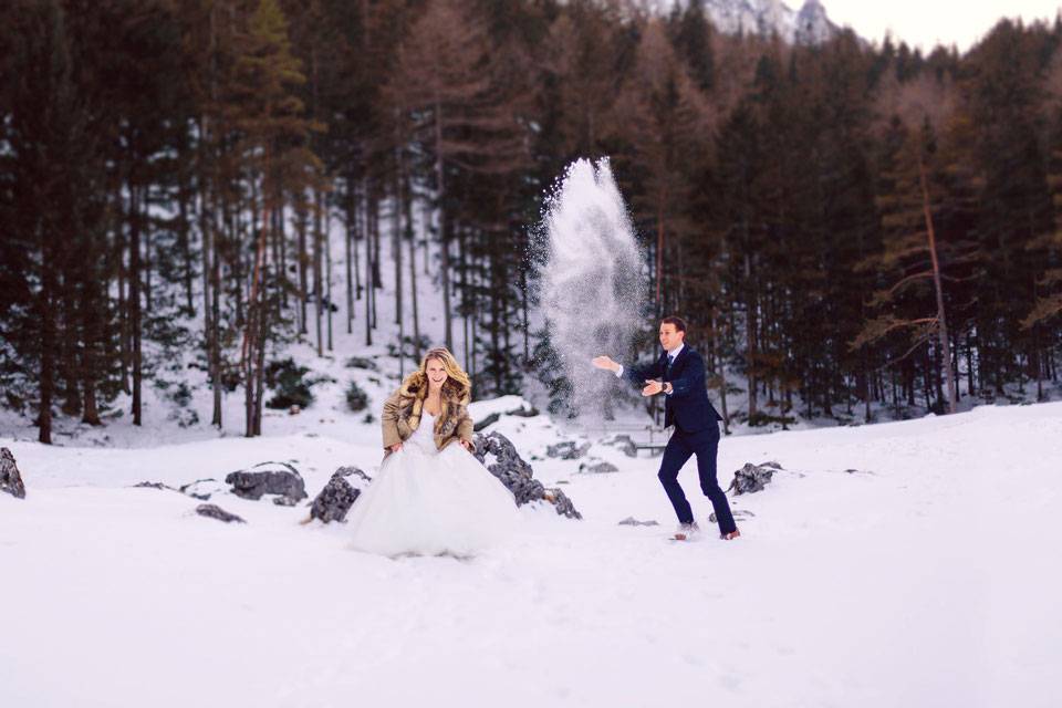Bräutigam bewirft Braut mit Schnee bei einem Wintershooting