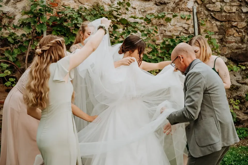 Wedding Planner Harald Winkler hilft der Braut gemeinsam mit den Brautjungfern bei einer Traumhochzeit