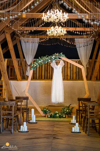 Traubogen aus Holz dekoriert mit Blumen und einem hängendem Brautkleid